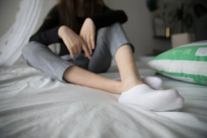 有一个女人坐在床上，双脚抬起