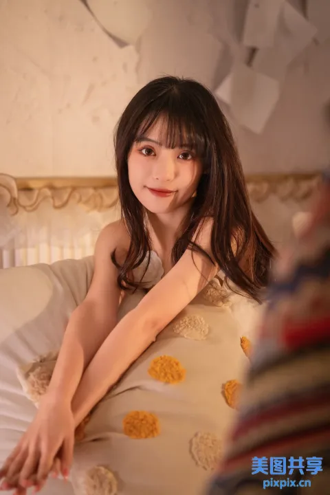 有一个年轻女孩躺在床上，手里拿着一个枕头