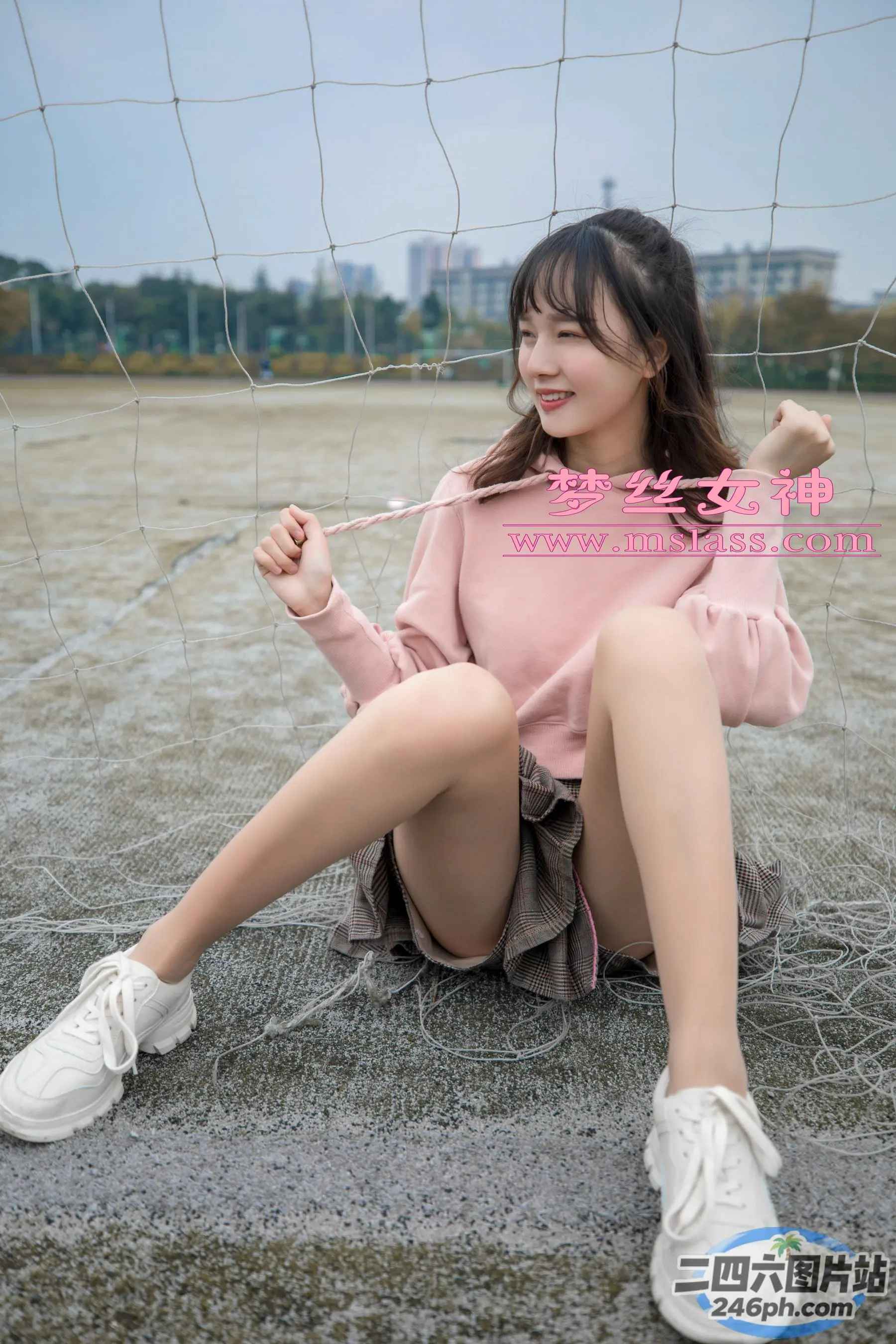 一名女子拿着网球拍坐在地上
