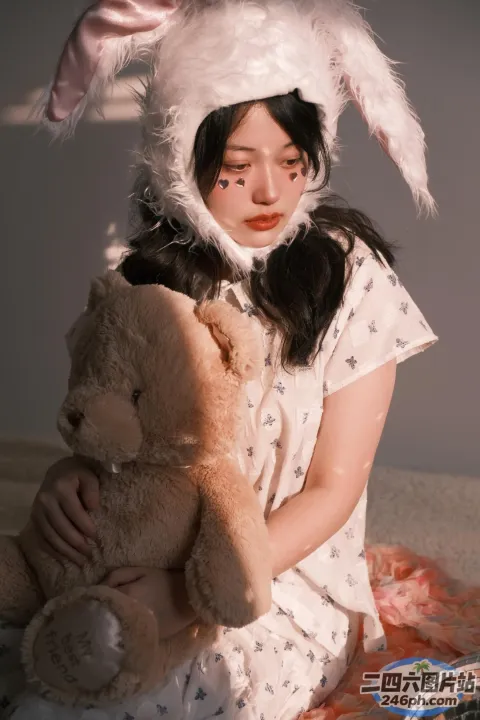 床上坐着一个女人，手里拿着一只泰迪熊