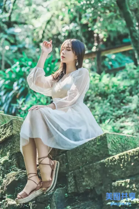 一个穿着白色连衣裙坐在石架上的女人