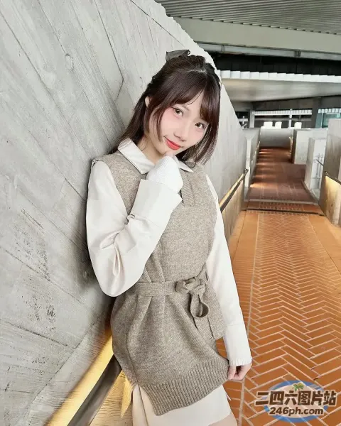 有个女人站在墙边，一只手搭在臀部上