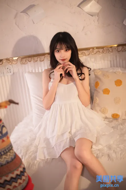 床上坐着一个穿着白色连衣裙的女人