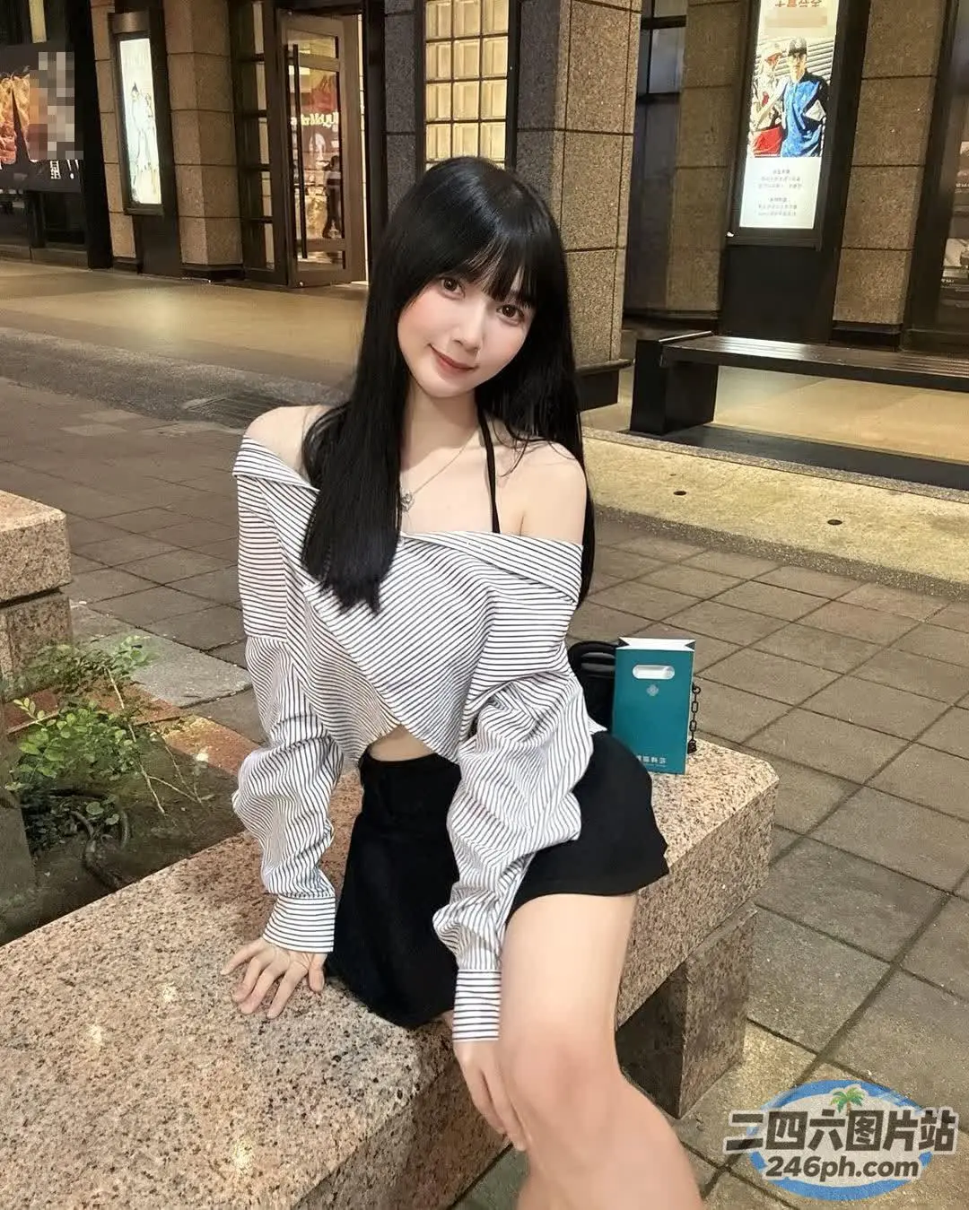 阿拉伯裔亚洲妇女坐在石凳上，手里拿着一杯咖啡