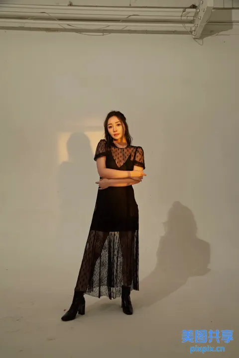 身穿黑色连衣裙和黑色靴子的阿拉夫德女人站在白色房间里