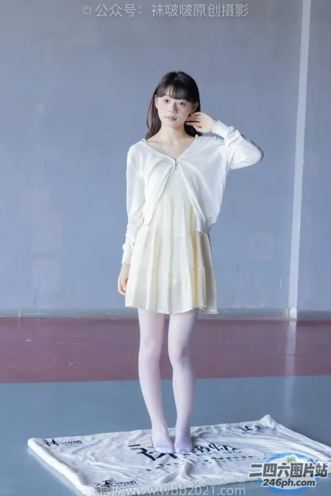 一个穿着白色连衣裙的女人站在白色毯子上