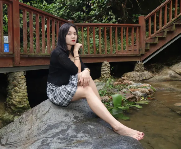 There is a woman on a rock in the water （有个女人坐在水中的一块岩石上）