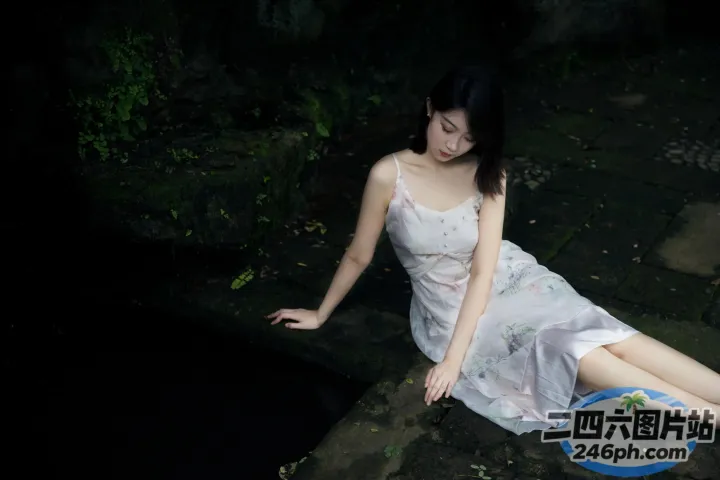 穿着裙子坐在池塘边的岩石上的阿拉夫德女人