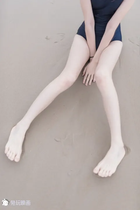 有一个女人坐在沙滩上，双腿交叉