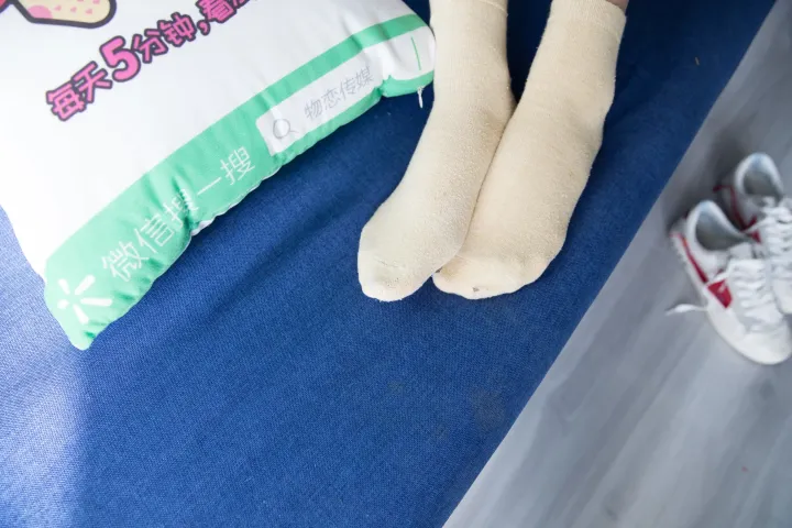 有人躺在床上，身上放着一个枕头和一双袜子