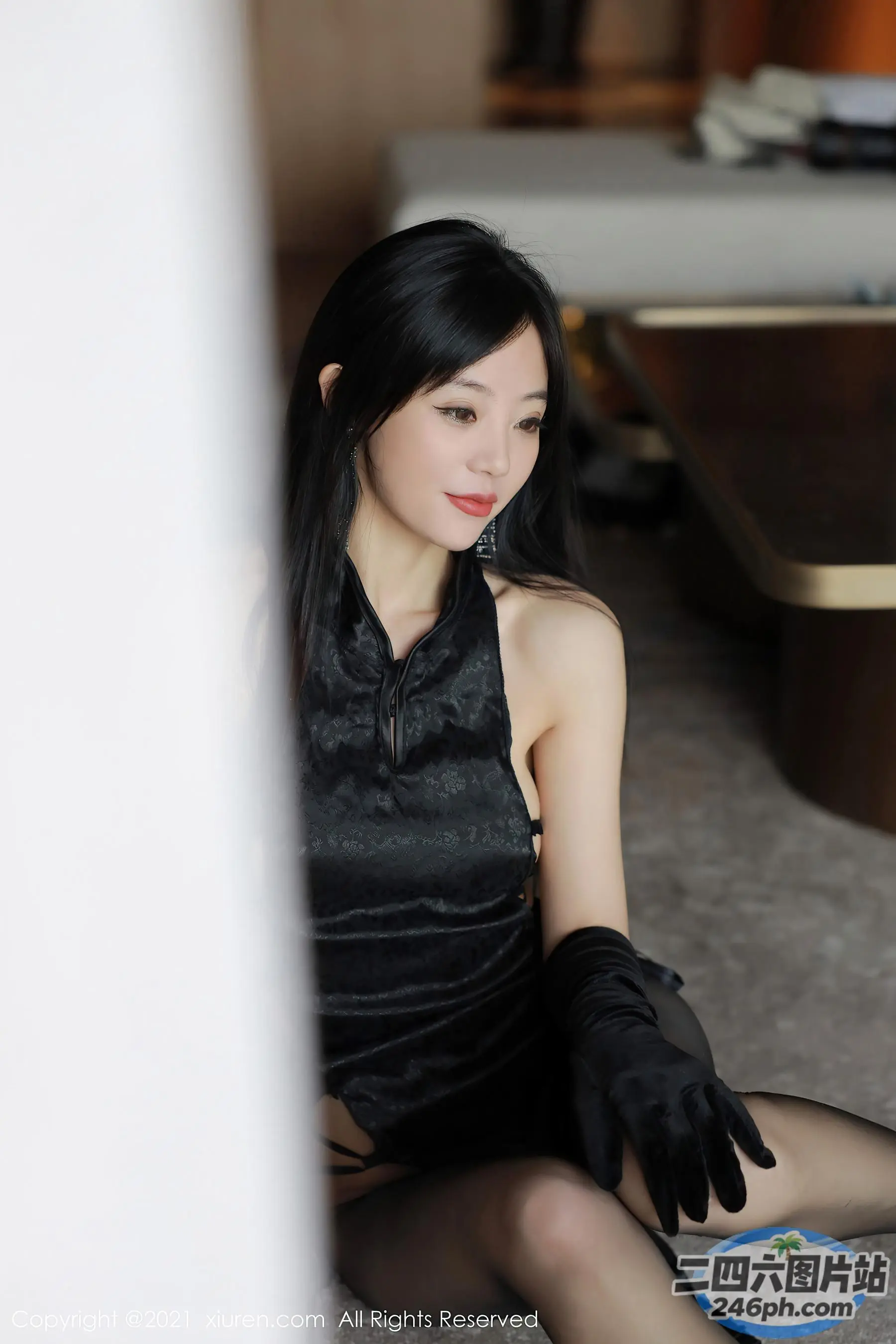 地板上坐着一个戴着黑色手套的女人