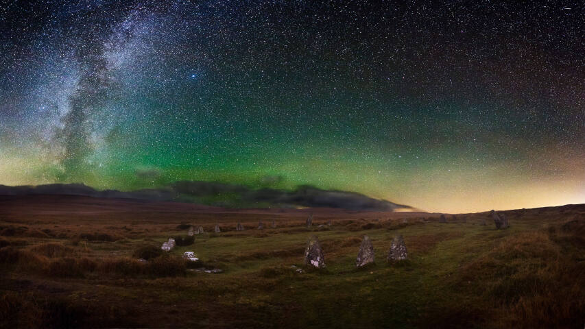星空，草地后面有绿色和紫色的极光