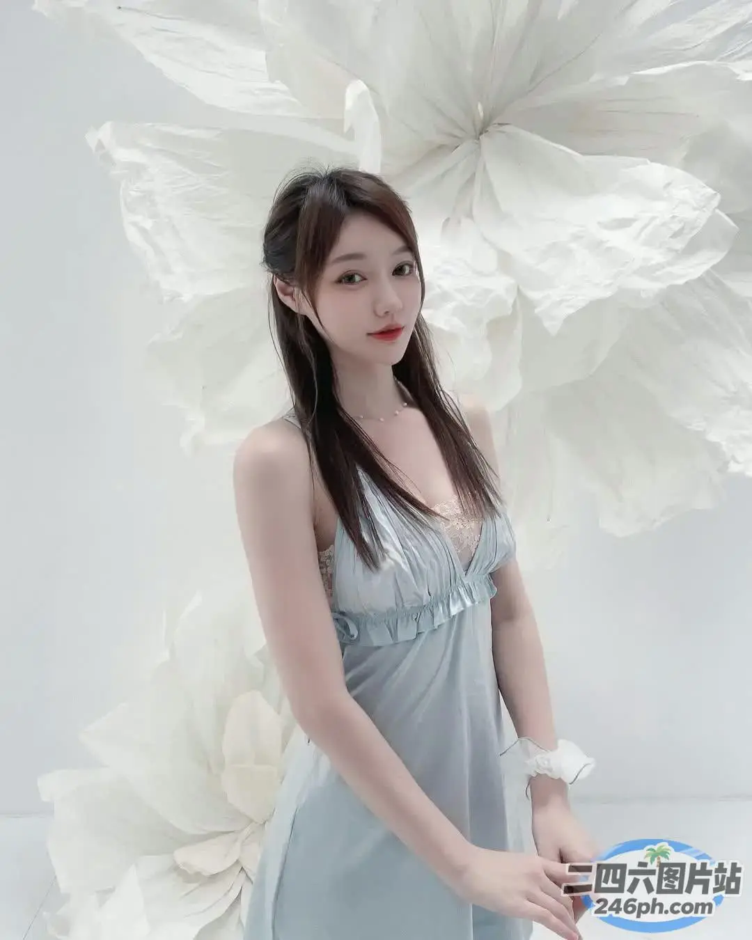 身穿蓝色连衣裙的 Araffe 女子在一朵大花前摆姿势