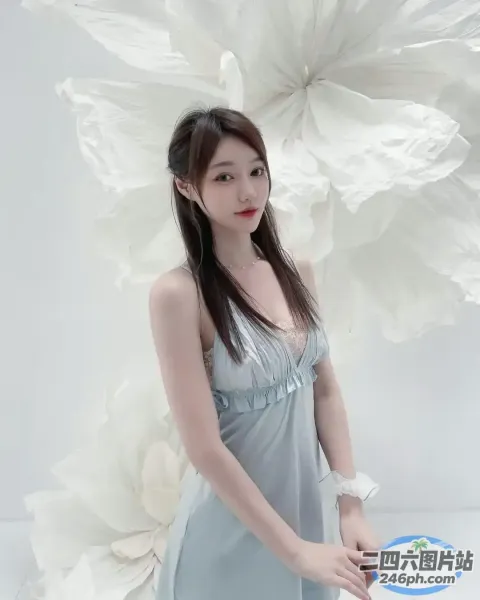 身穿蓝色连衣裙的 Araffe 女子在一朵大花前摆姿势