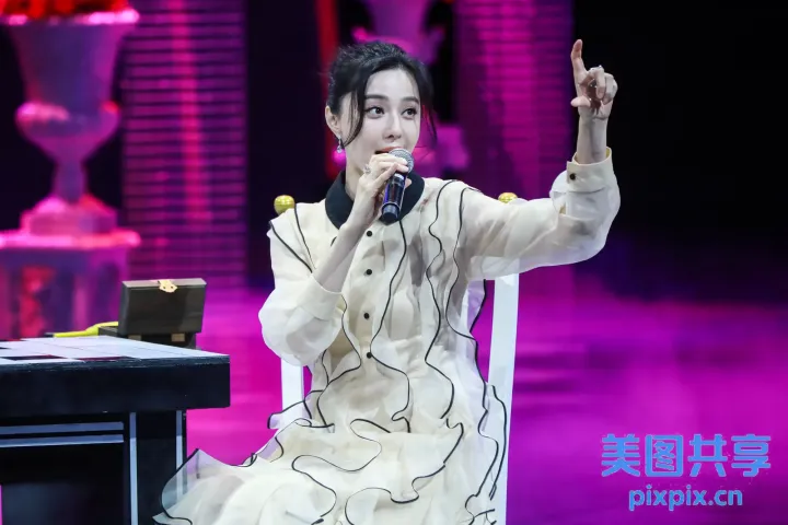 身穿白色连衣裙的阿拉夫女人坐在椅子上拿着麦克风