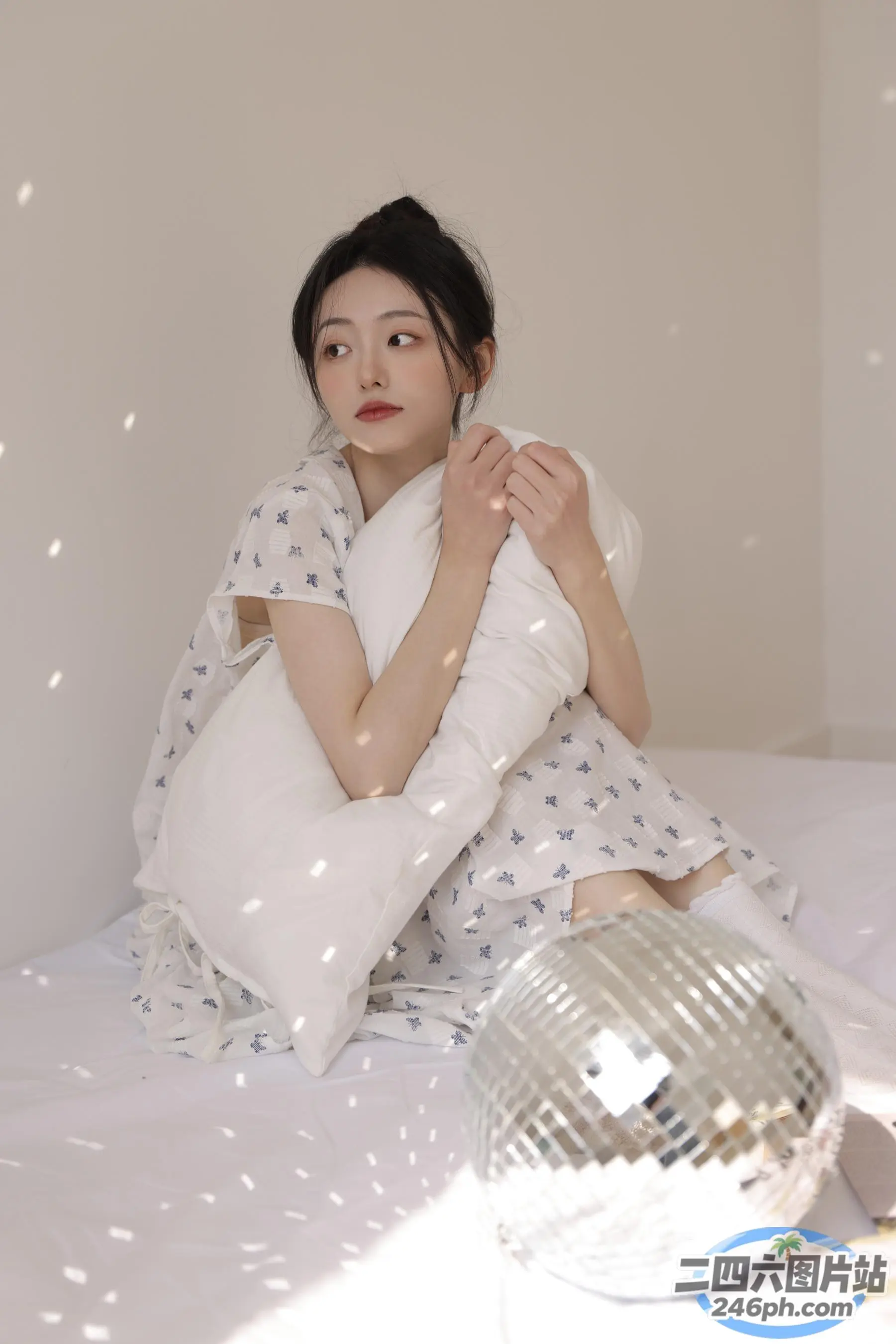 阿拉菲女人坐在床上，手里拿着枕头和迪斯科球