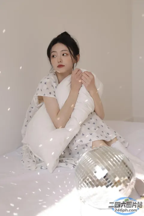 阿拉菲女人坐在床上，手里拿着枕头和迪斯科球