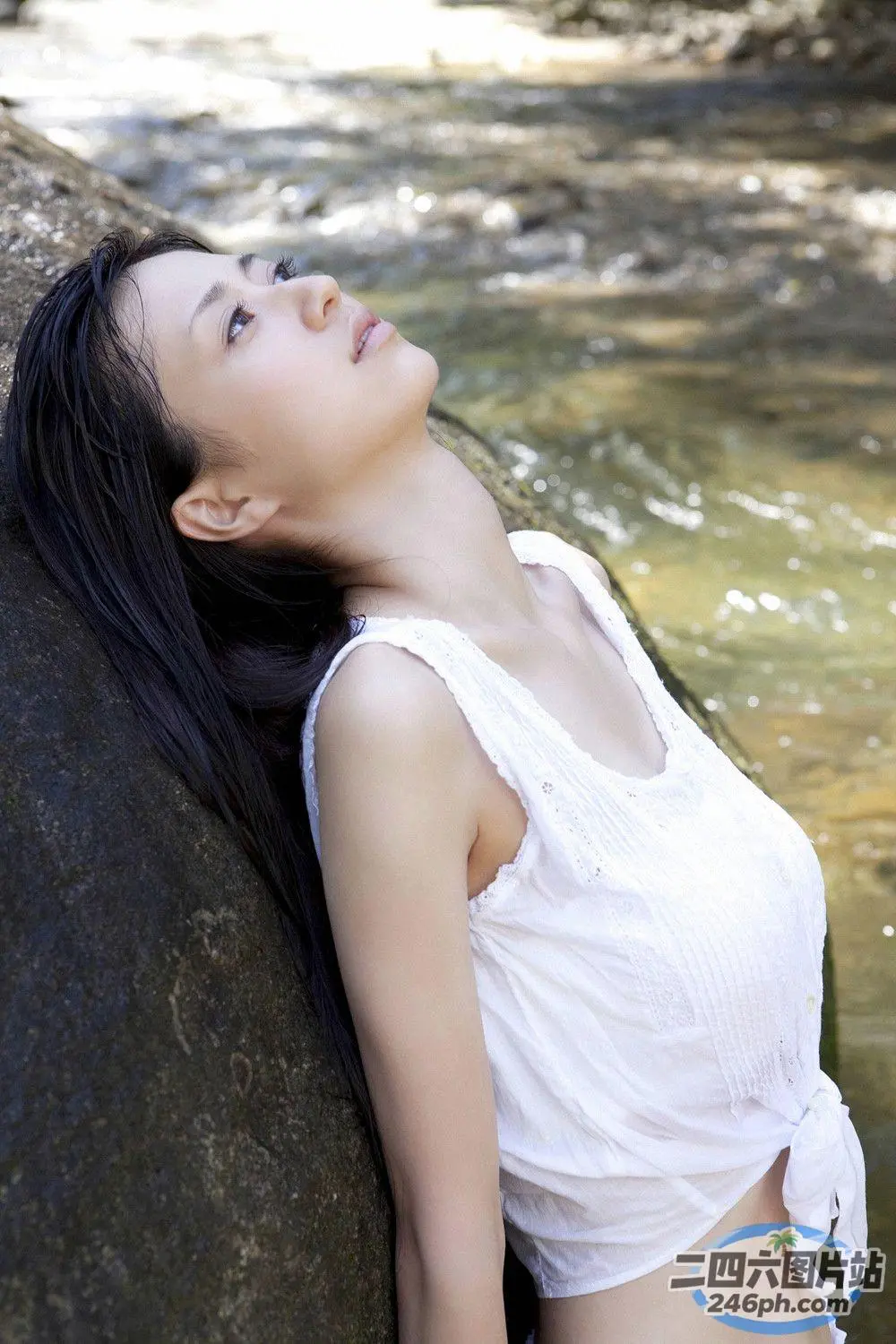 阿拉菲德亚洲妇女靠在河中的一块岩石上