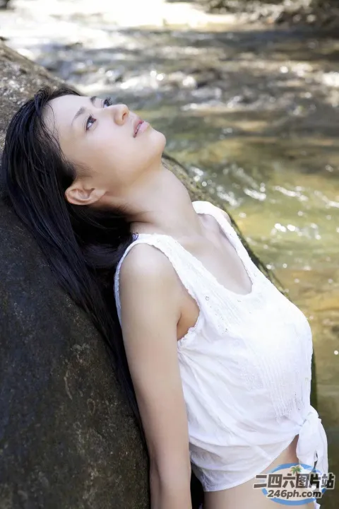 阿拉菲德亚洲妇女靠在河中的一块岩石上