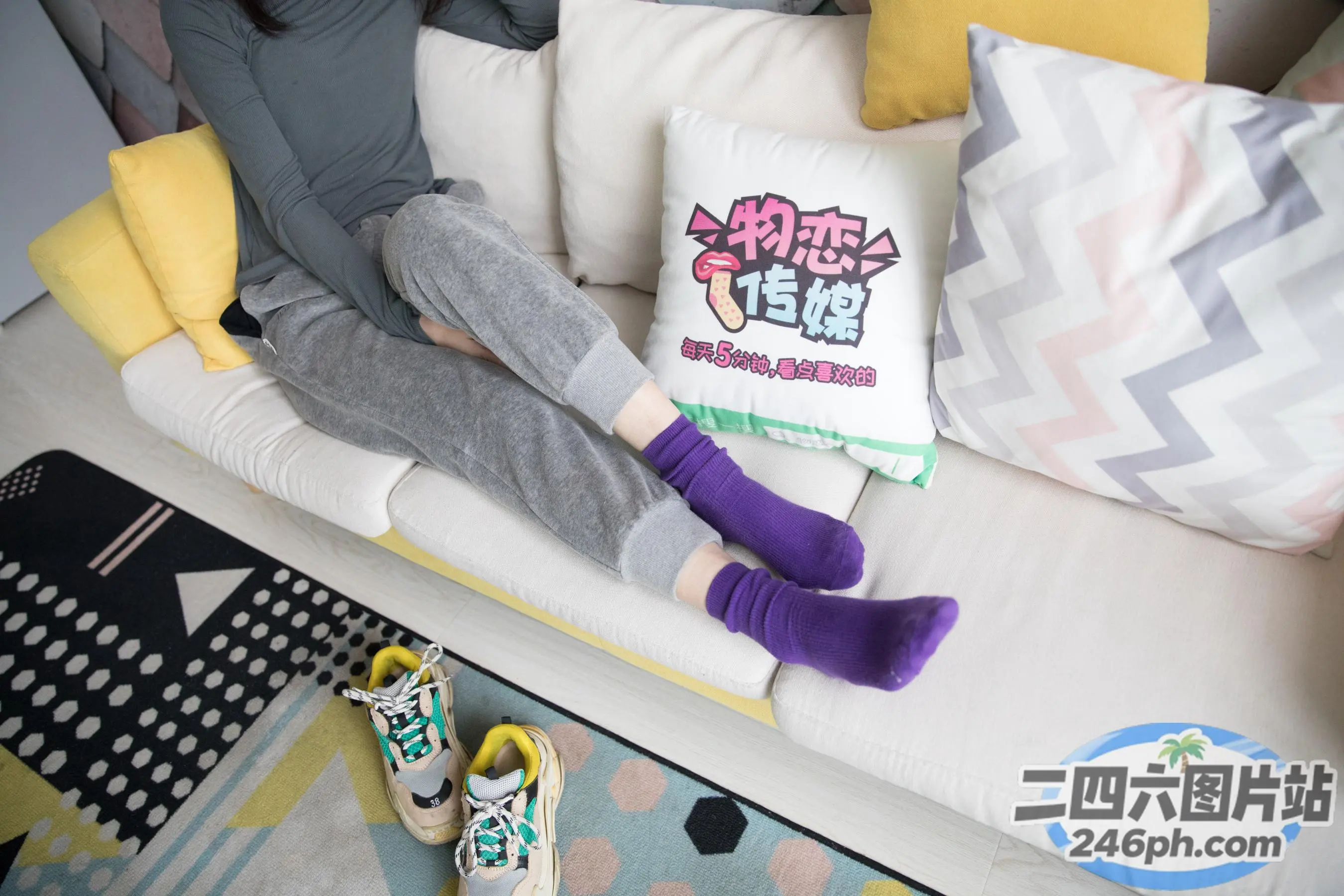 Araffe 坐在沙发上，手里拿着一个枕头和一双紫色的袜子