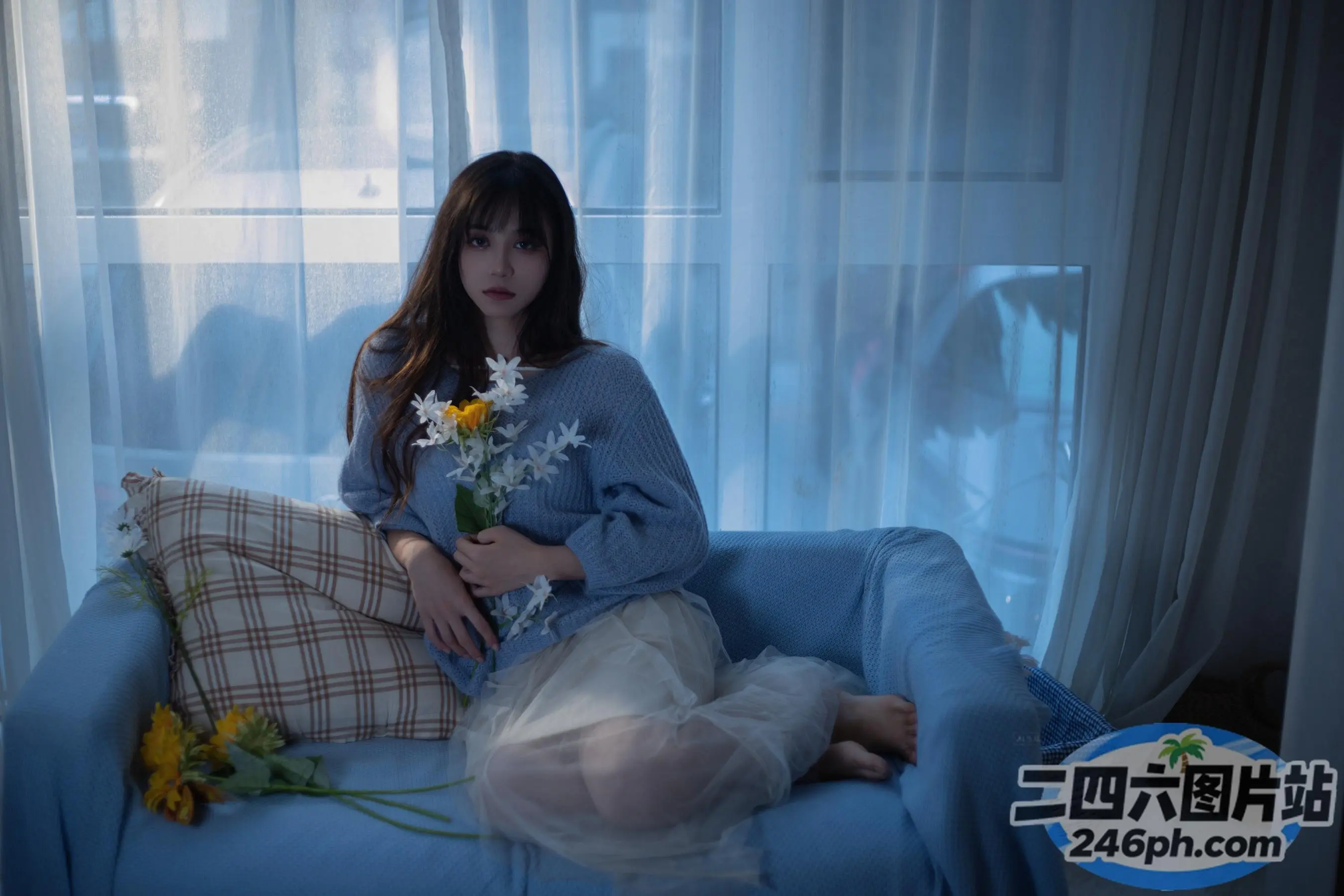有一位女士坐在沙发上，手里拿着一束鲜花