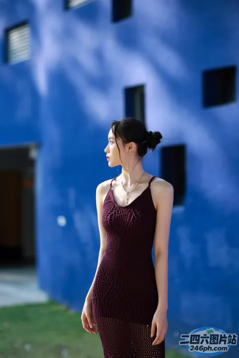 一个穿着裙子的女人站在一栋蓝色的建筑前