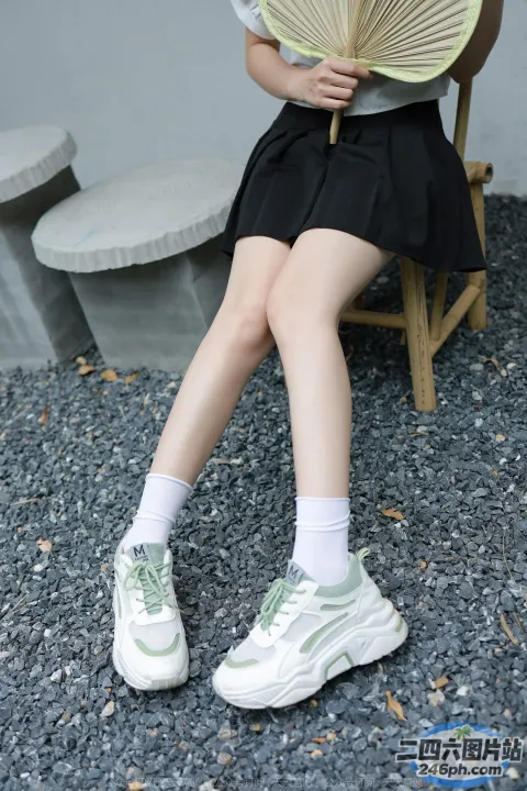 有一位女士坐在椅子上，手里拿着一把风扇