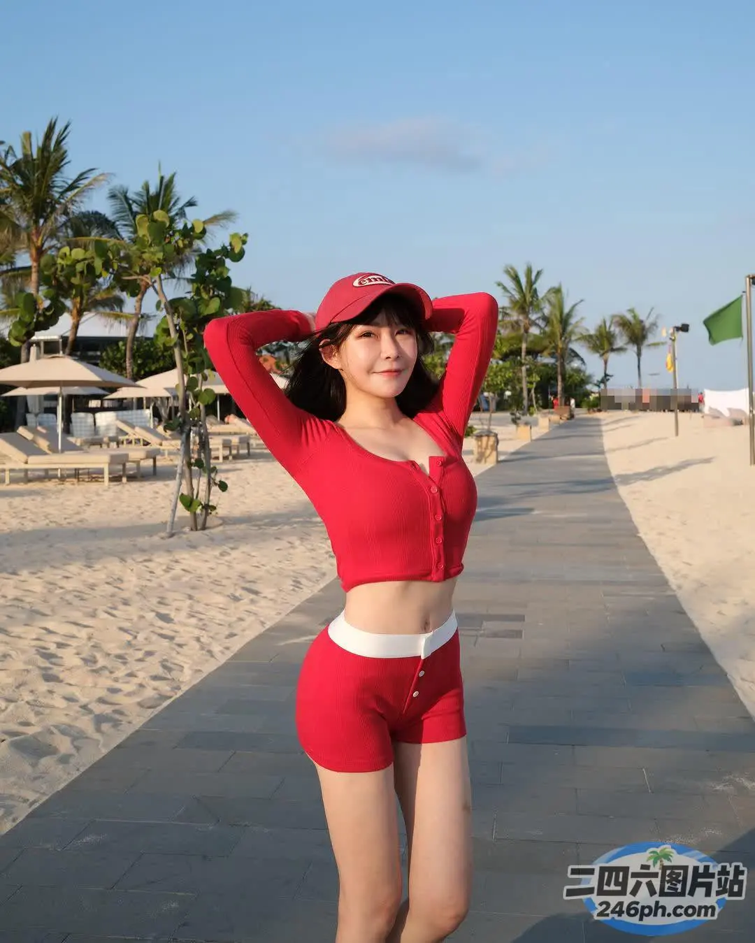身穿红色运动服的女子戴着帽子在海滩上摆姿势