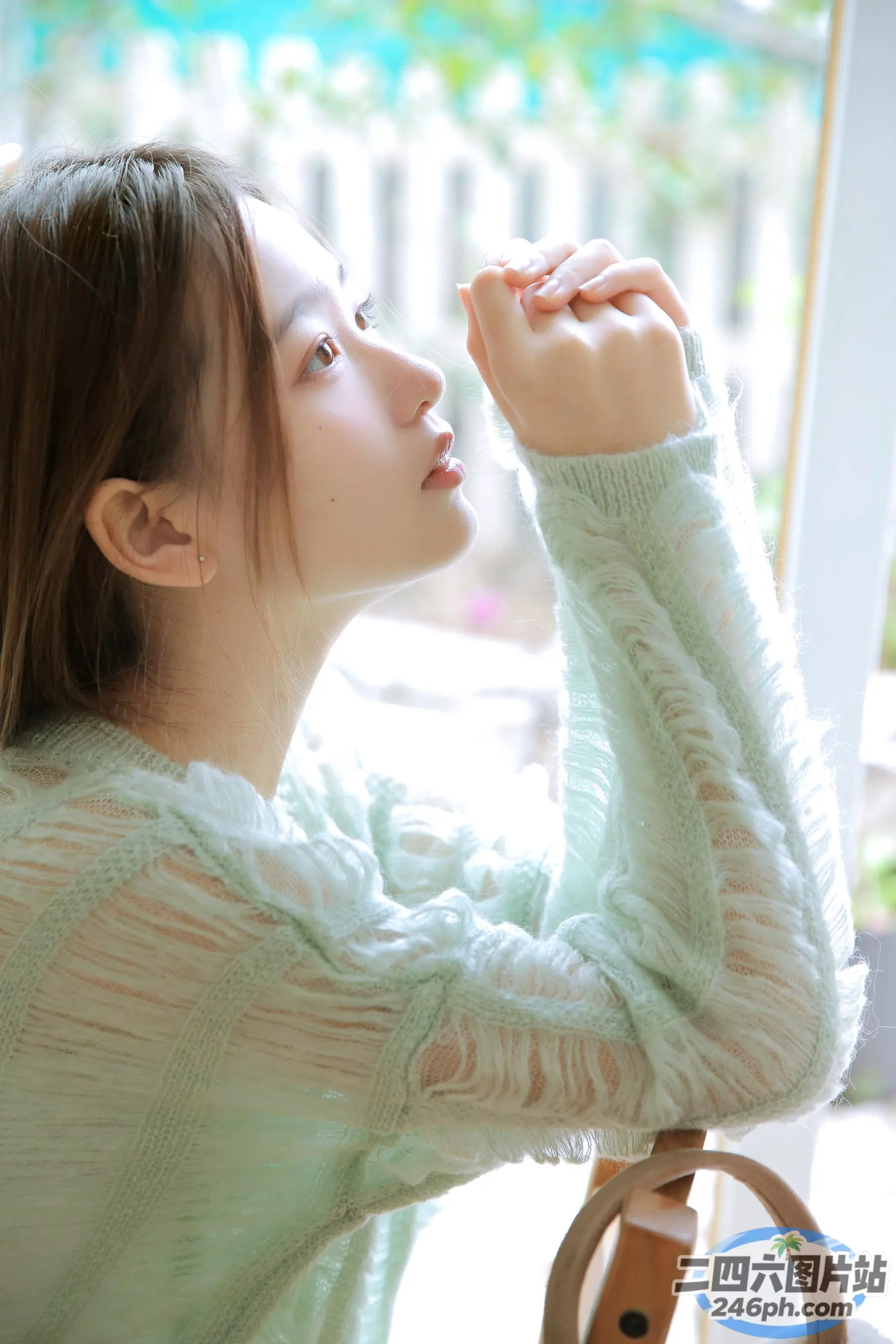 穿着绿色毛衣的 Araffed 女人坐在桌子旁