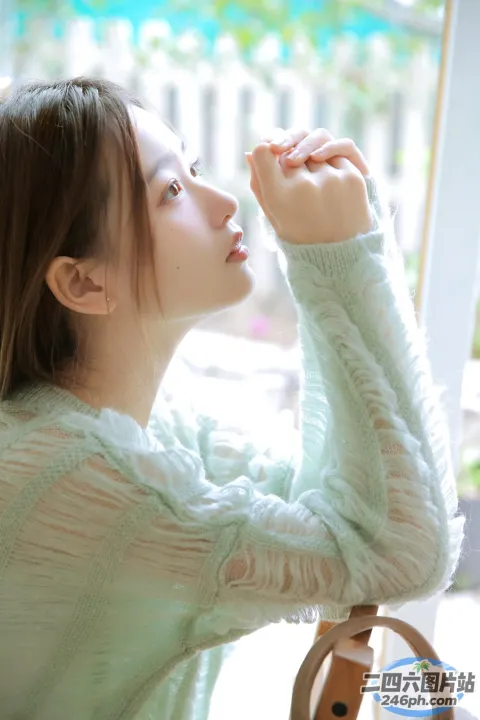 穿着绿色毛衣的 Araffed 女人坐在桌子旁