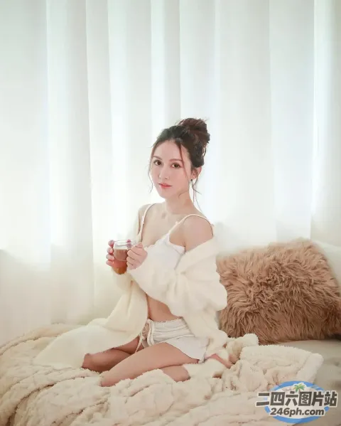 床上坐着一个女人，手里拿着一个杯子