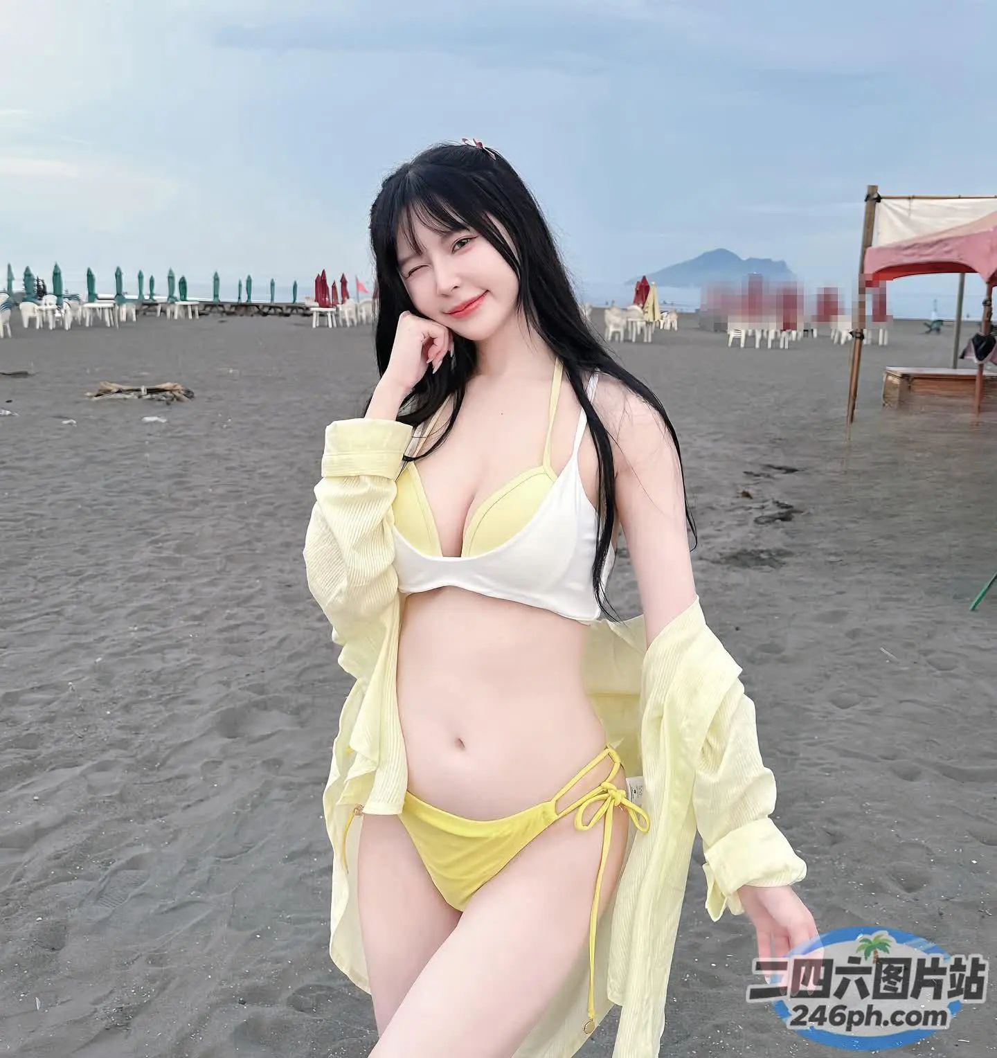 有个穿着黄色比基尼的女人在沙滩上摆姿势