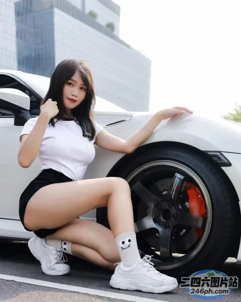 一名女子坐在一辆白色跑车旁的地上