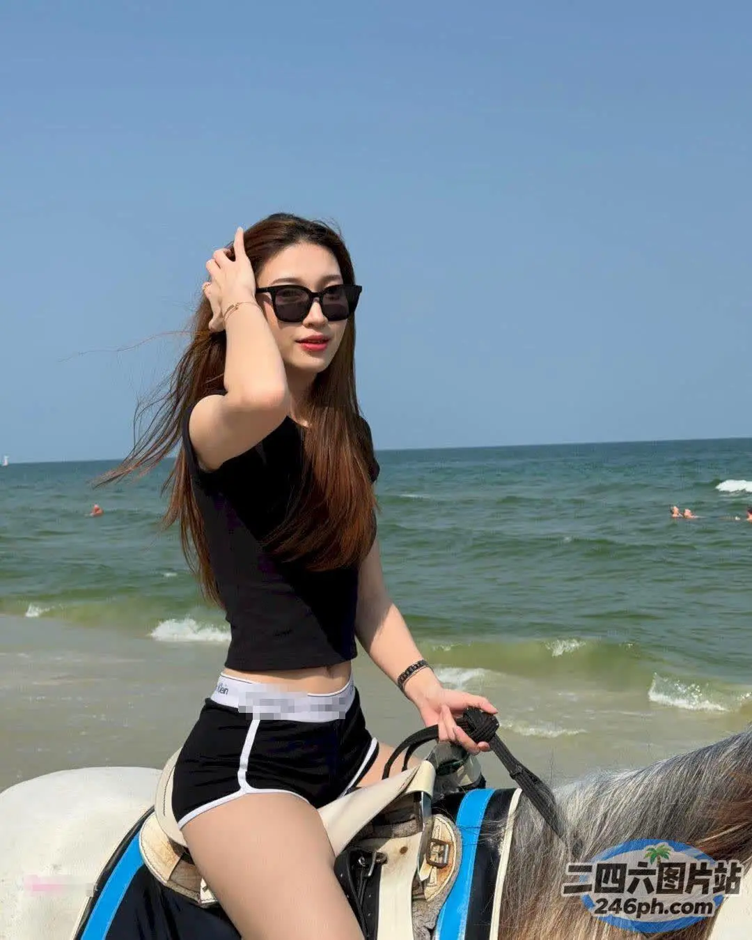 黑衣女子在海滩上骑着白马