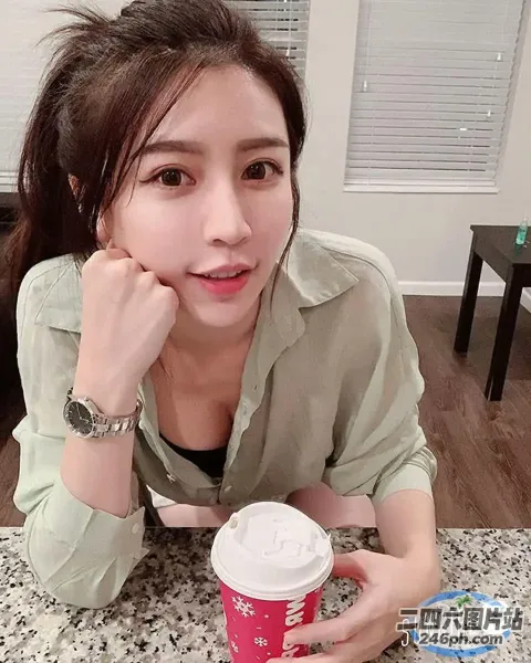 阿拉菲女人坐在桌子旁，手里拿着一杯咖啡