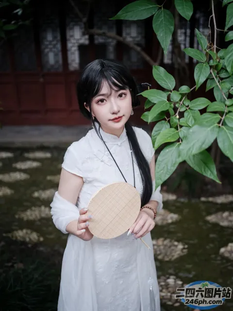 有个身穿白色连衣裙的女人，手里拿着一把木扇