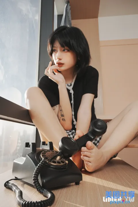 地板上坐着一个女人，手里拿着电话