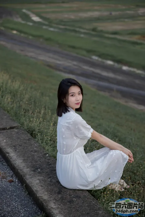 有一个女人穿着白色的裙子坐在路边