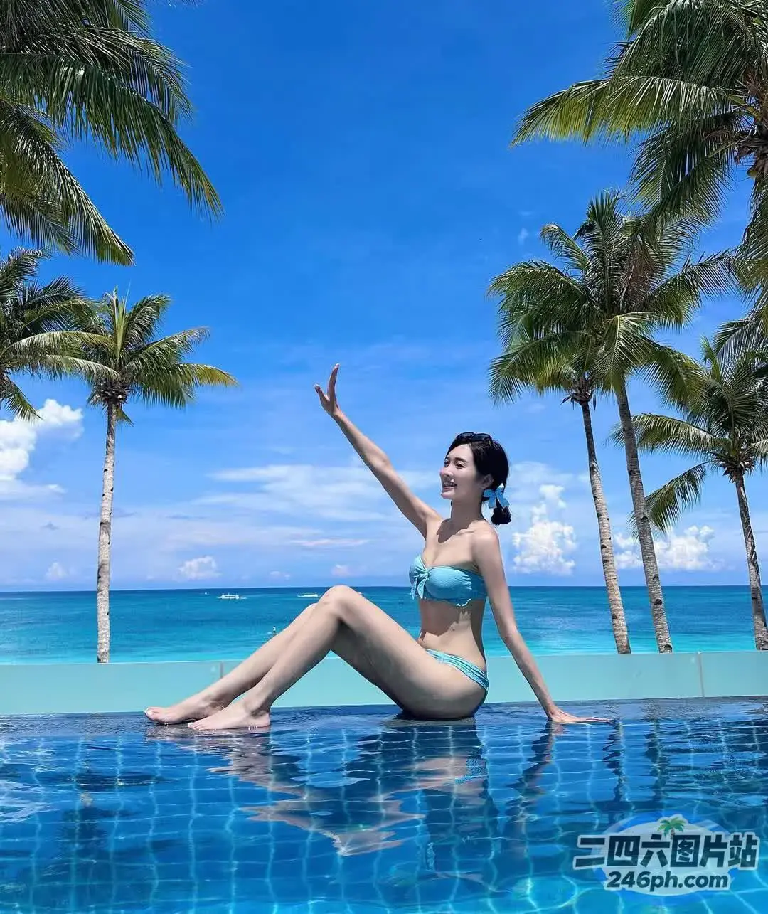一个穿着比基尼的女人坐在棕榈树的游泳池上