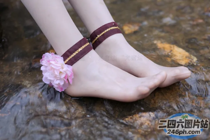 有一个女人站在一块岩石上，脚踝上挂着一朵花