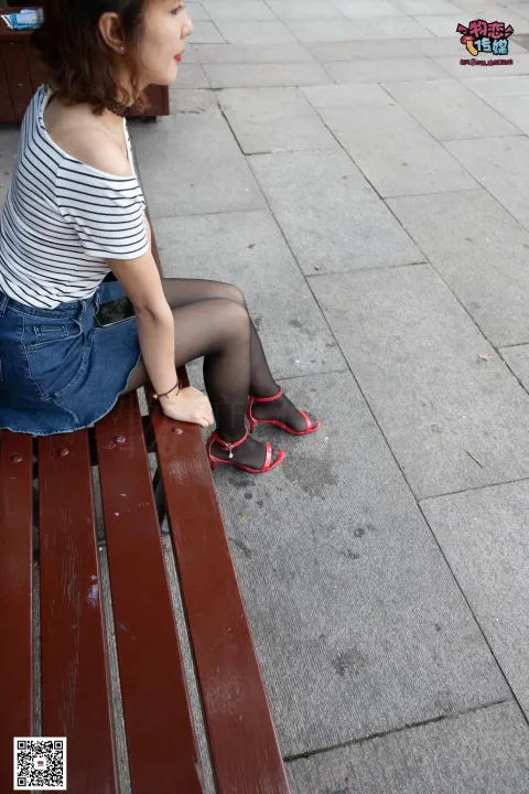 有个女人戴着耳机坐在长凳上