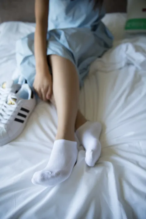 有一个女人坐在床上，双脚抬起