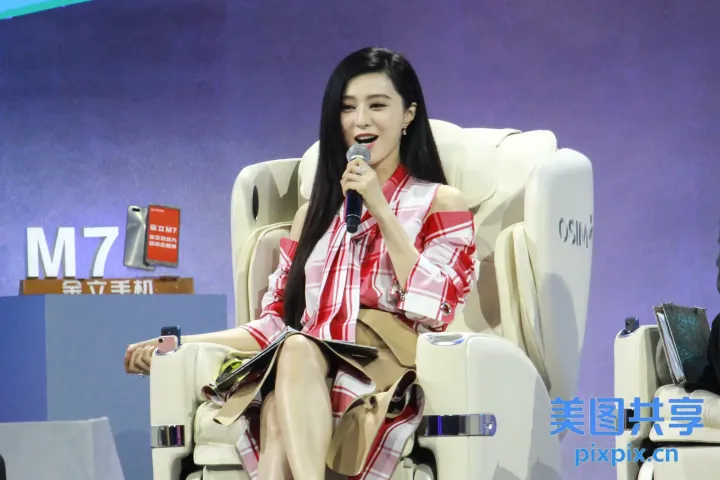 坐在椅子上，手里拿着麦克风的女人