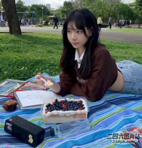 阿拉菲女孩躺在毯子上，手里拿着蛋糕和一本书