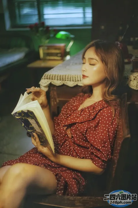 穿着红色连衣裙坐在椅子上看书的女人