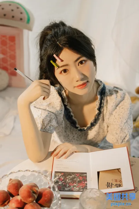 桌旁坐着一个女人，手里拿着一本书和一支笔