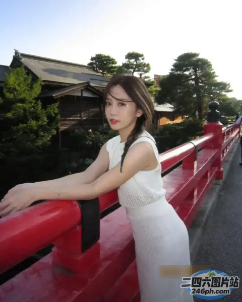 身穿白色连衣裙的阿拉夫德女子靠在红色栏杆上