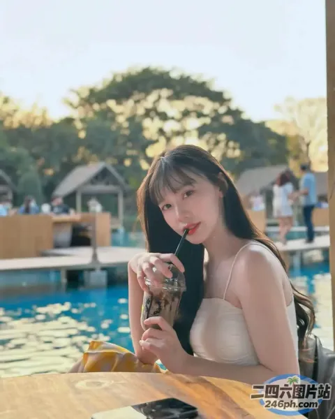 阿拉菲女人坐在泳池边的桌子旁喝酒
