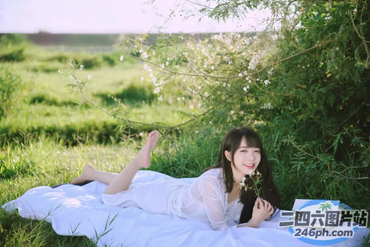 阿拉菲女人躺在田野里的毯子上，手里拿着一本书