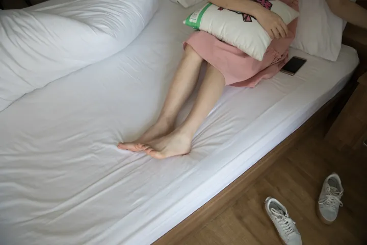 有个女人躺在床上，手里拿着一个枕头